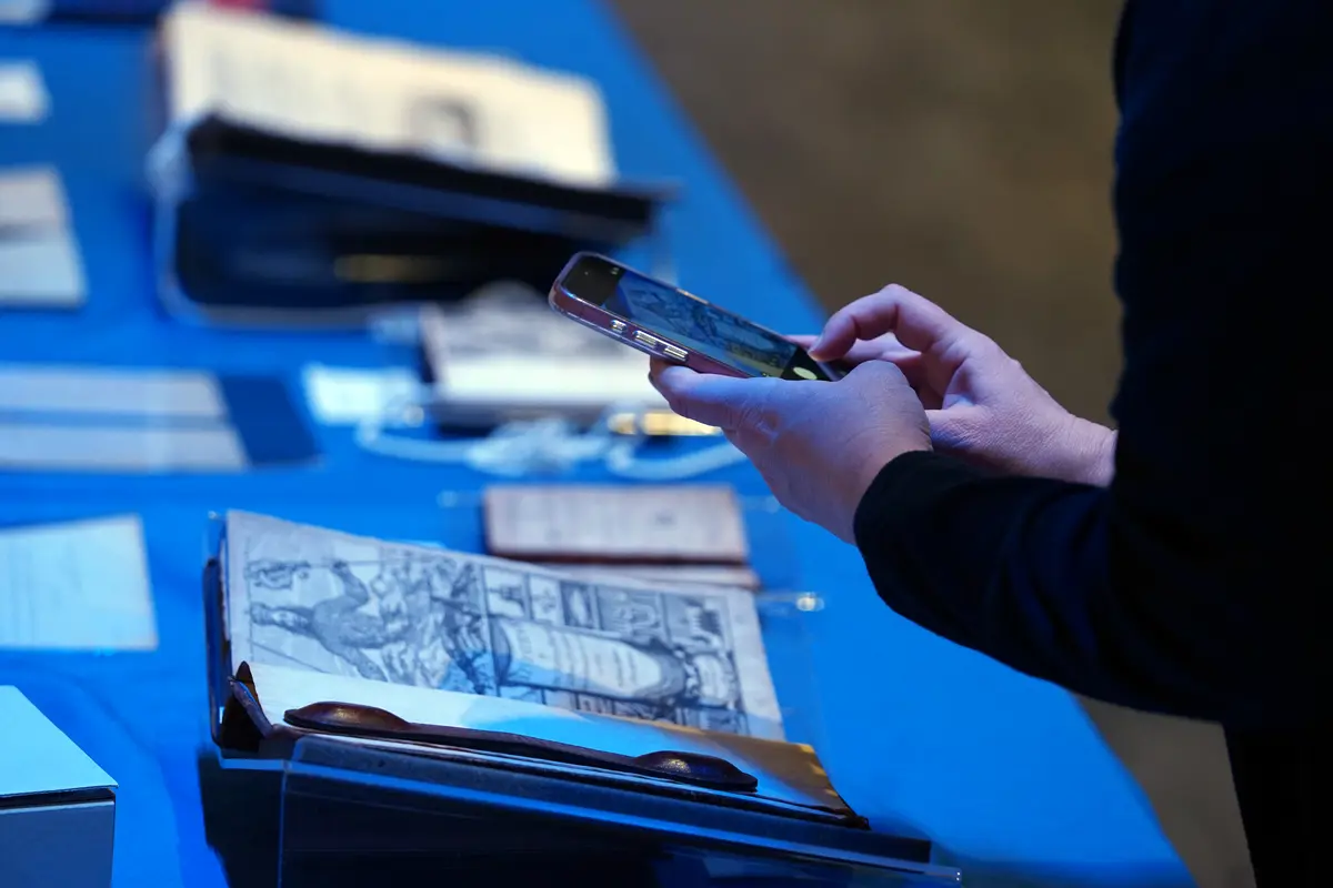 A person takes a photo of an old book with their mobile phone.