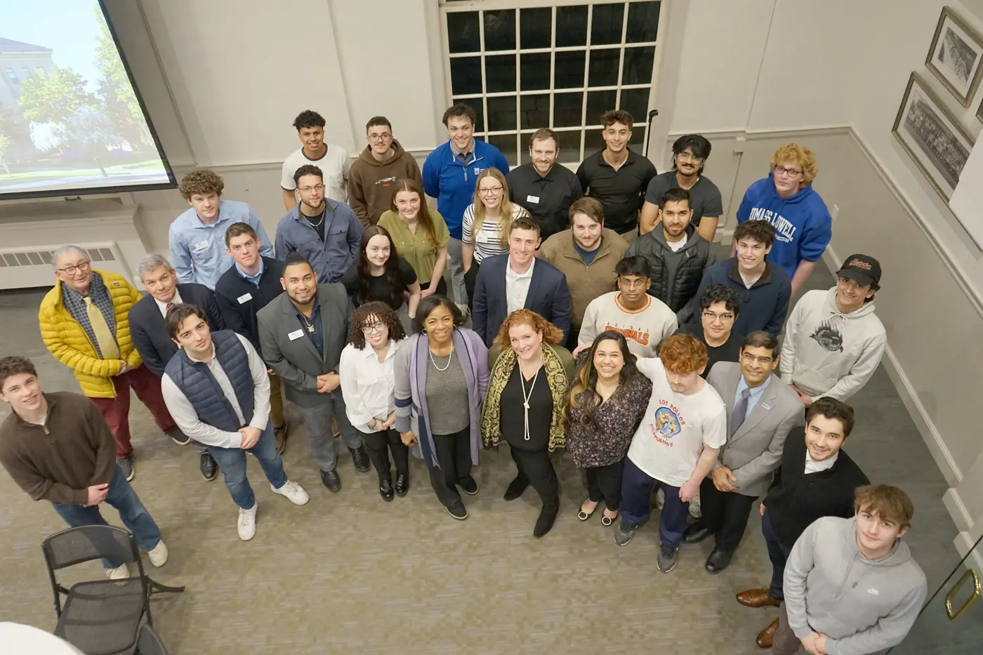 A group of about 30 people look up and pose for a photo.