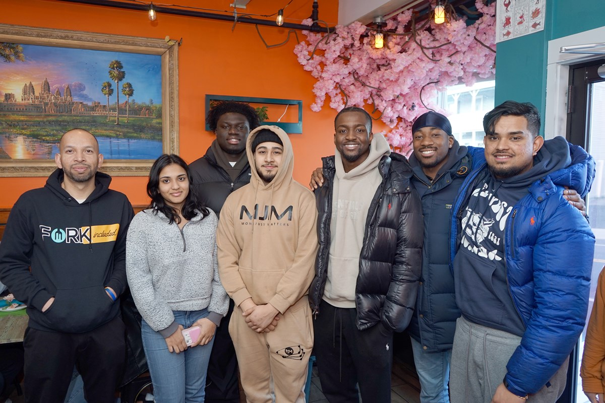 Six men and a woman pose for a group photo inside a restaurant.