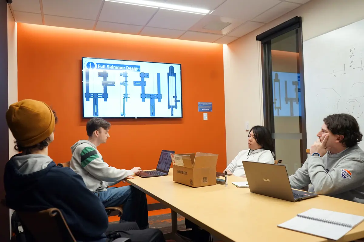 Four young men sit around a conference room table and work on a project.