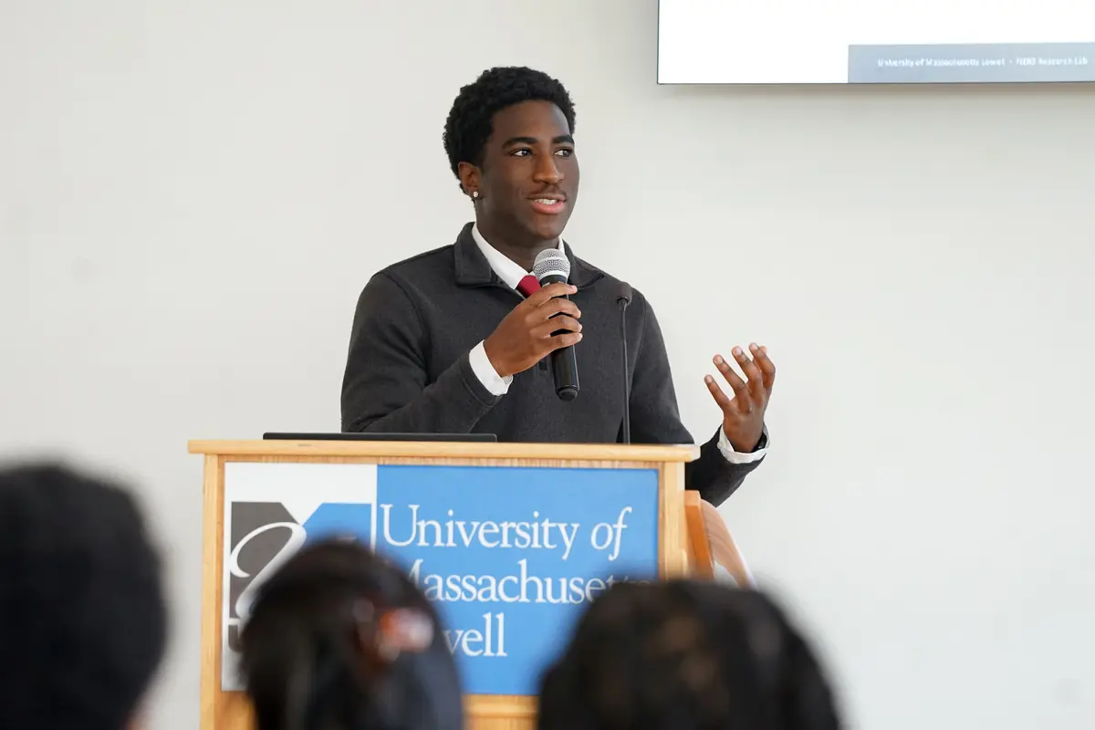 Three people stand in front of a research poster and talk in a room.