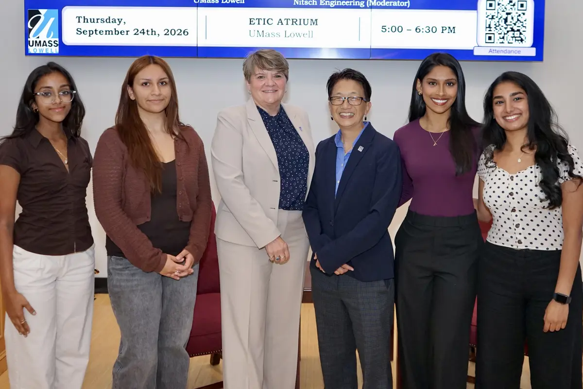 Six women pose for a group photo in front of a screen.