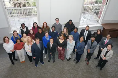 Two dozen people look up and pose for a group photo.