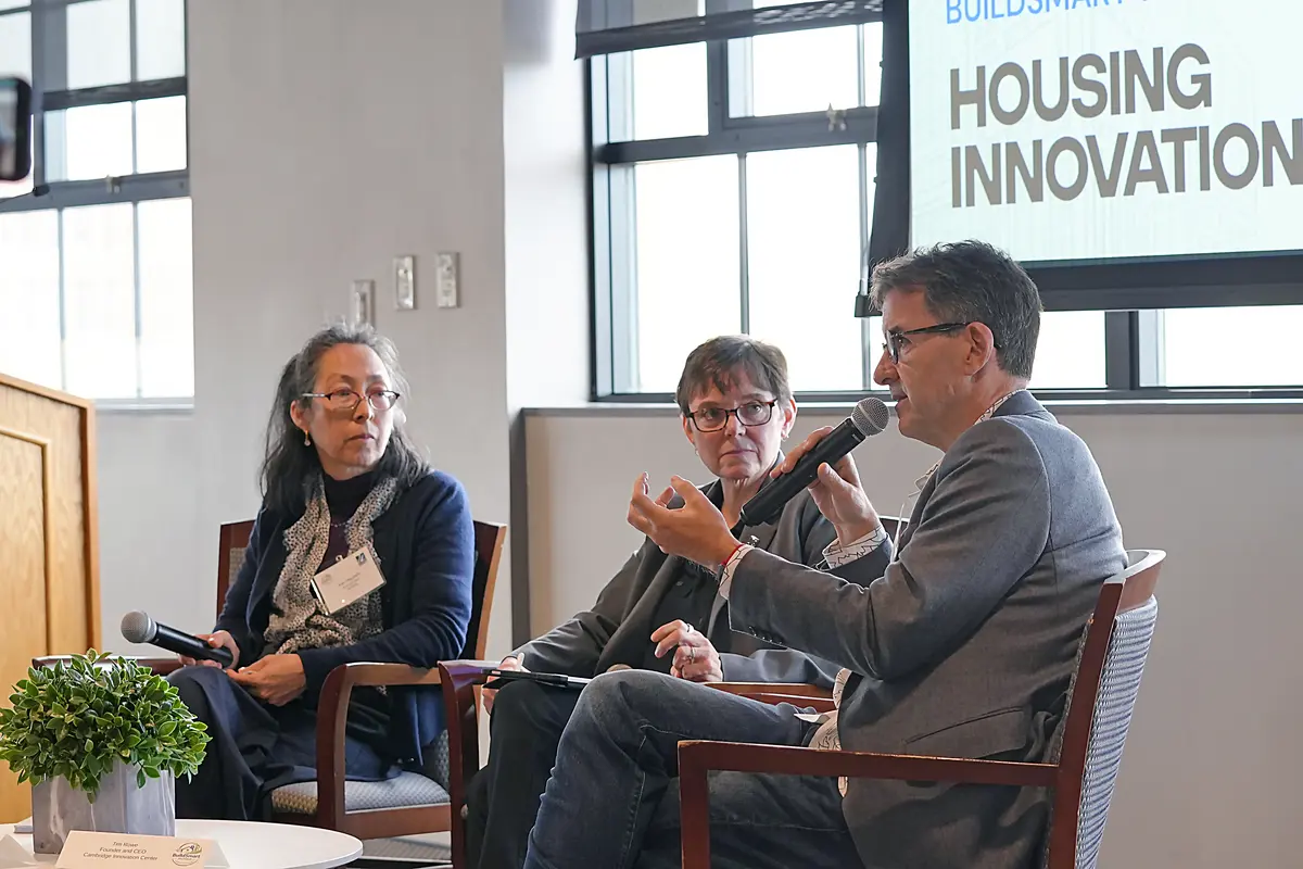 Three people sit on a panel at a housing innovation summit.