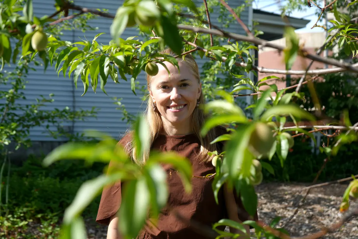 Jasmina Burek stands behind a peach tree.