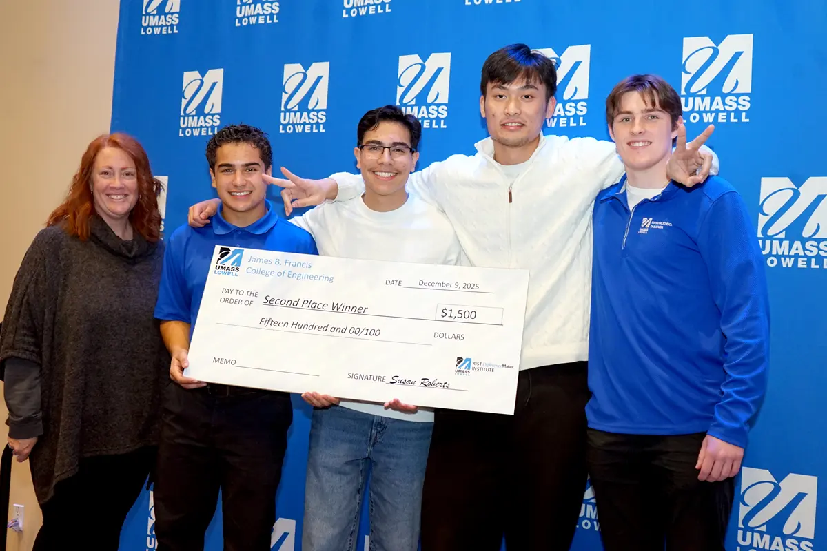 A woman poses for a photo with four college students who are holding a jumbo check.