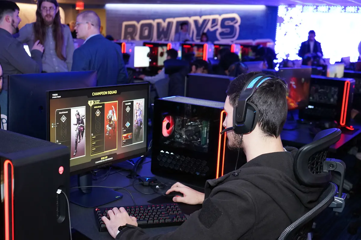 A college student wears a headset while playing a PC video game in an esports arena.