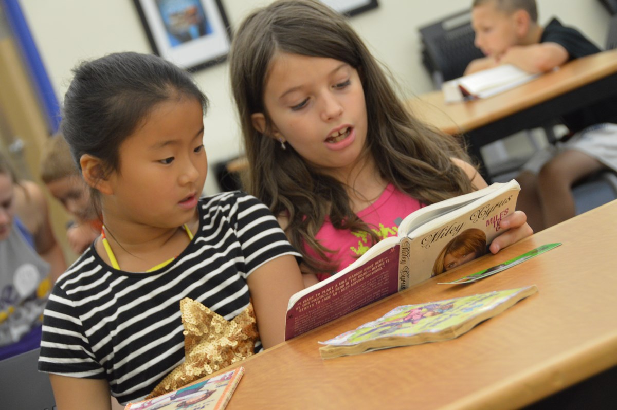 Two young girls read a book