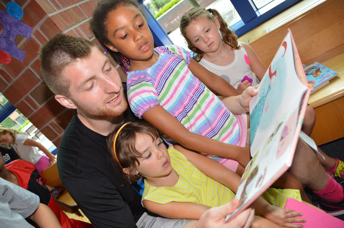 Male counselor reads book to young girls
