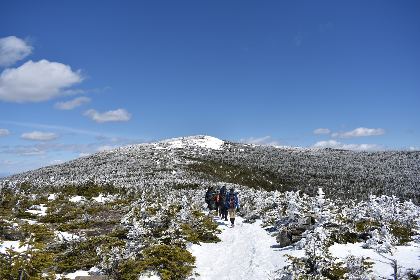 Student walking towards mountain in snow on outdoor hiking trip.
