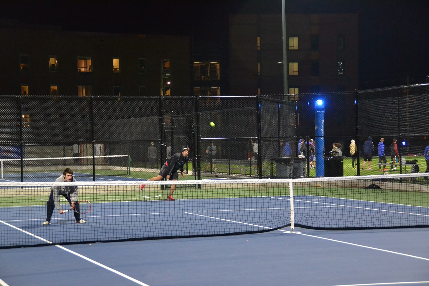 Students playing tennis under the lights at CRC complex.