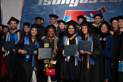 Manning School of Business students hold up their diploma covers.