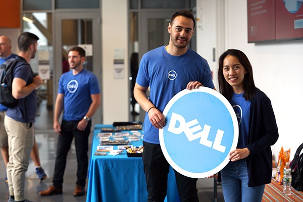 Business grad Mai Pham and engineering alum Nabil Saleh hold a Dell sign in the Pulichino Tong atrium