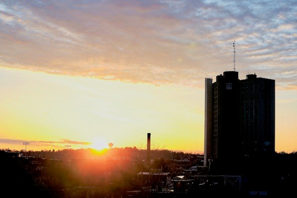 the sun rises behind Fox Hall and East Campus