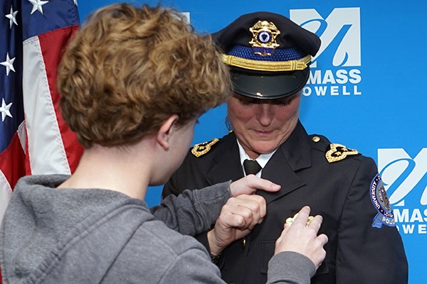 A young man pins a police badge on his mom during a ceremony