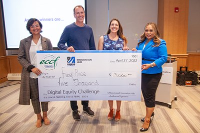 A man and three women hold an oversized check while posing for a photo