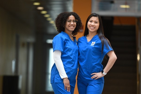 Dimoeri Diaz and Taylor Chau pose for a photo at UML in blue scrubs