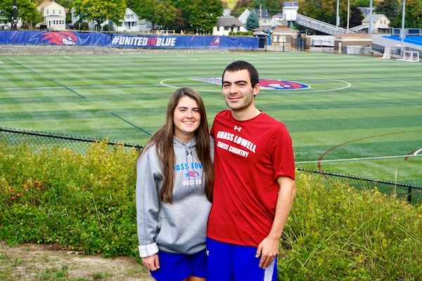 Siblings Abby and Ben Drezek stand in front of the UML soccer pitch