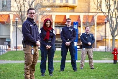 Four student EMTs stand in front of Fox Hall