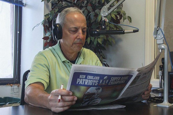 Man reading newspaper into microphone