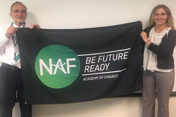 Fred Press and Lori Capra unveil a banner announcing the new NAF Academy of Finance at Haverhill High.