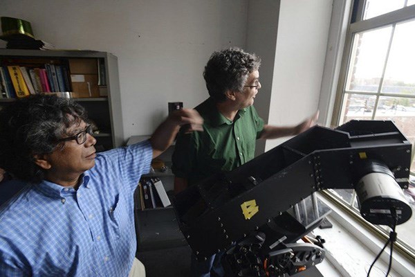 UMass Lowell physics professors Tim Cook, left, and Supriya Chakrabarti work on equipment.