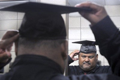 Luis Estevez of Lawrence adjusts his graduation cap
