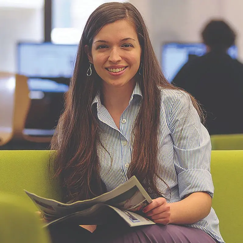 Person smiles while holding a newspaper.