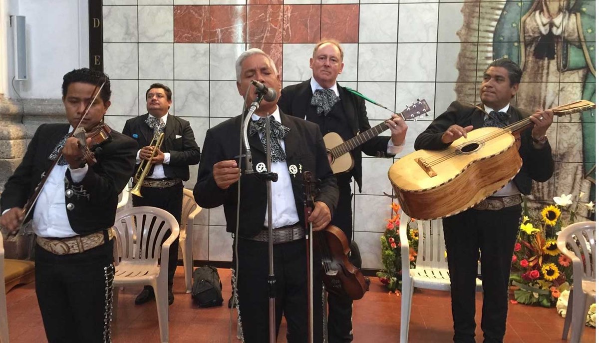 Ed Priest plays guitar with other musicians in a mariachi band.
