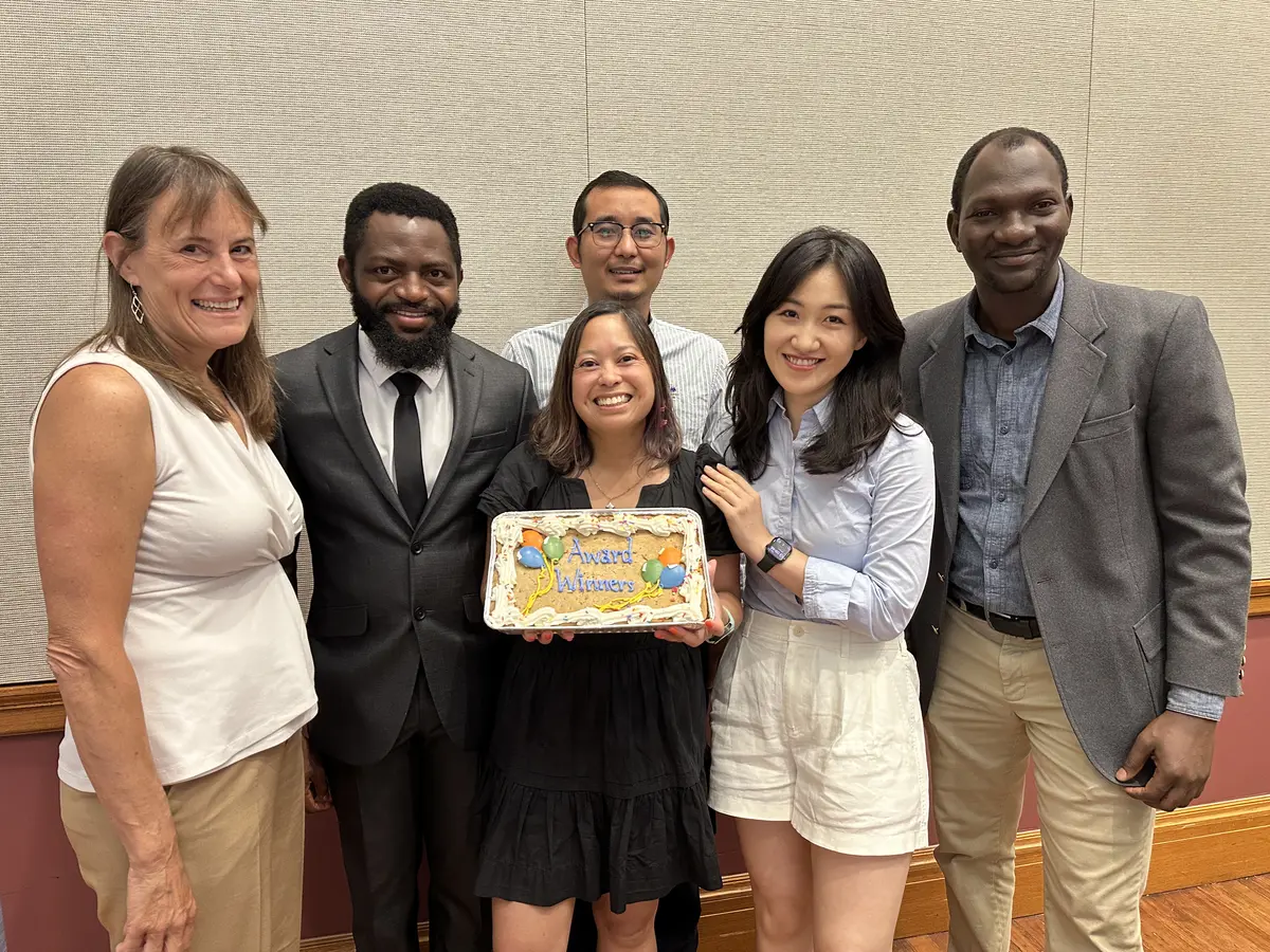 Four research and evaluation in education Ph.D. students and two education faculty members pose with a cake