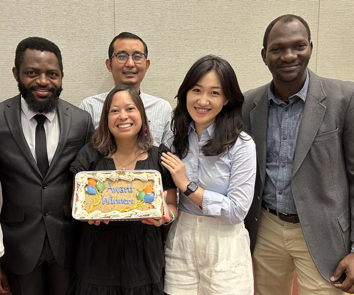 Four research and evaluation in education Ph.D. students and an education faculty members pose with a cake.