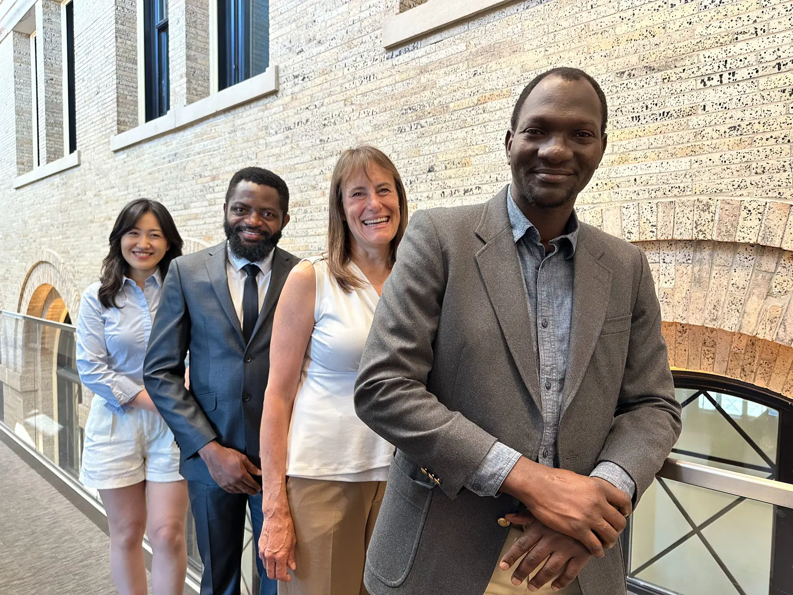 Three education research and evaluation Ph.D. students and Associate Dean Jill Hendrickson stand against a railing