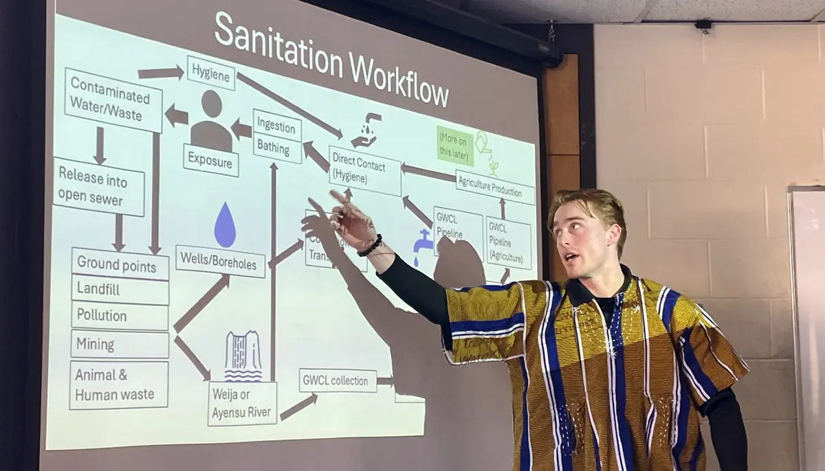 Elliot Johnson delivers a presentation as he points to a diagram entitled "Sanitation Workflow."