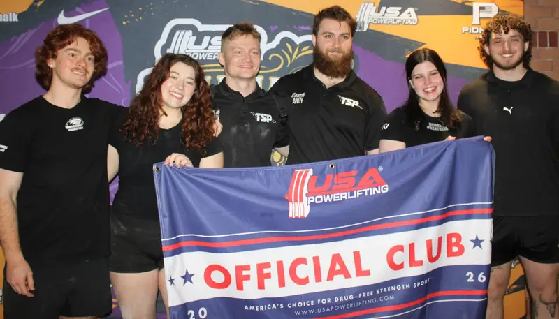 Emily Willard in a group holding a banner that says USA Powerlifting Official Club.