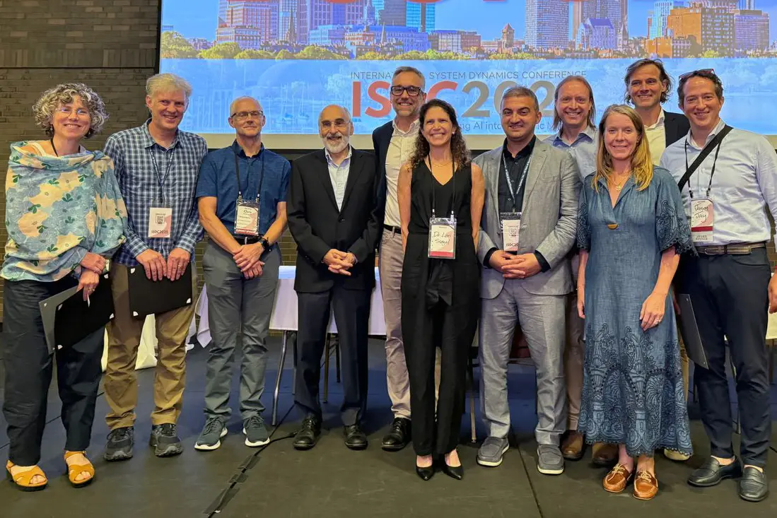 Eleven people pose for a photo at a conference.