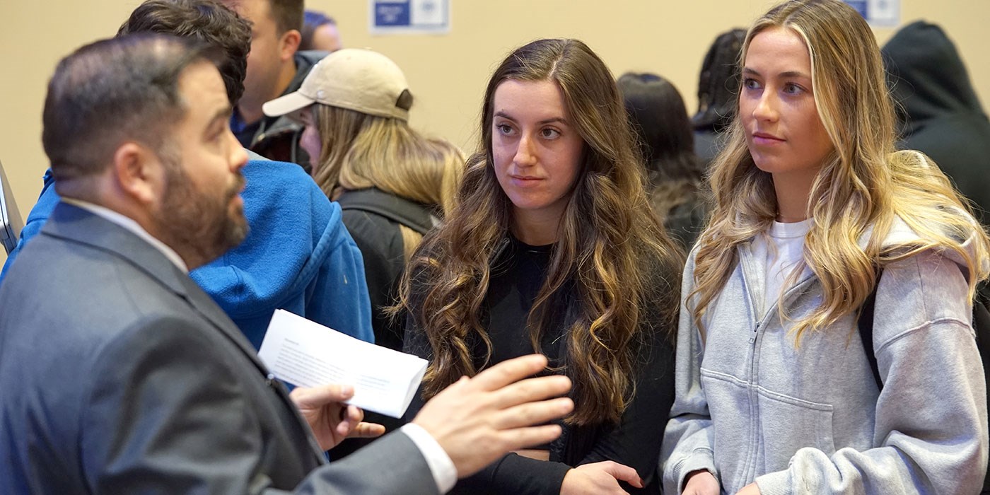 Two young women listen to a man talk at Ethics Fest