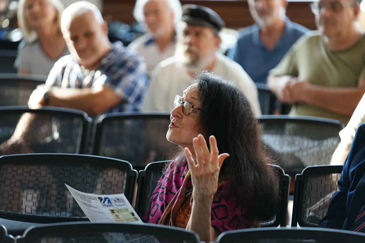 Michelle Lavallée Berti talks and gestures from her chair. Others are sitting behind her listening