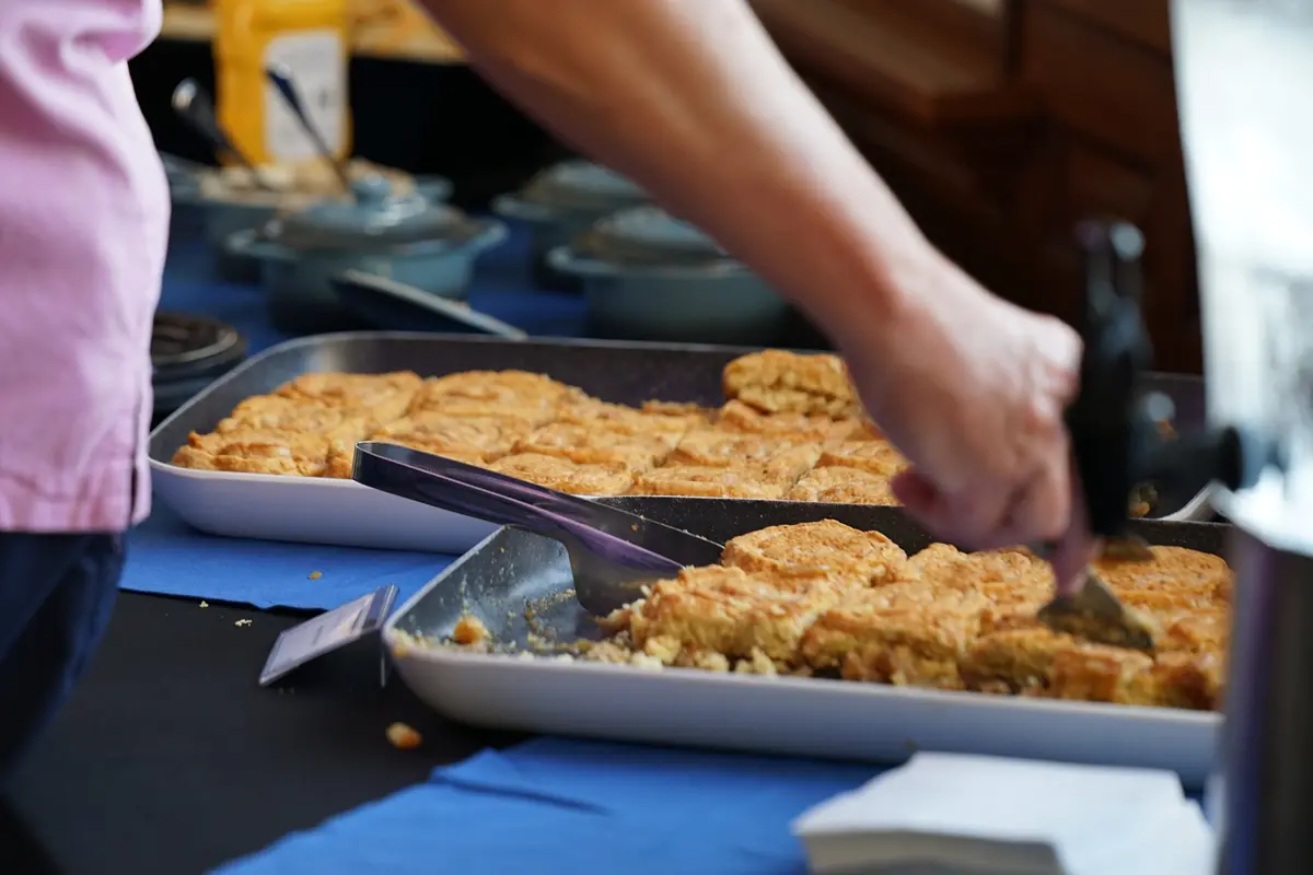 A woman's hand uses a spatula to lift a pastry from a cookie sheet onto her plate