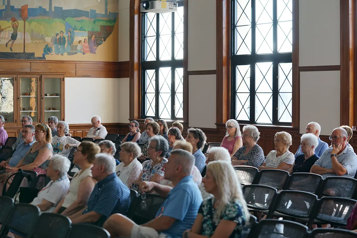 A mostly older crowd of Franco Americans sit in chairs in Coburn Hall
