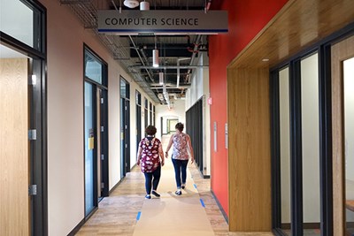 Two people walk down the hall of the third-floor computer science offices at Dandeneau Hall