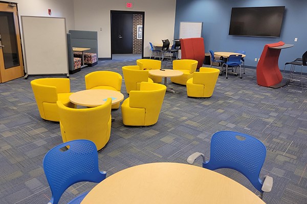 A student lounge with yellow and blue chairs