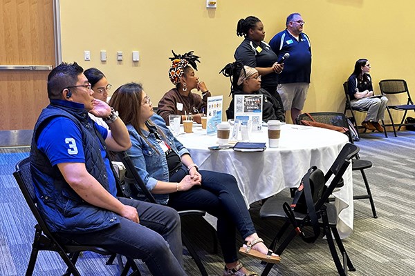 Family members and UML's director of family programs and services Marshall Greenleaf, along with student workers, listen to a presentation during a UMass Lowell family orientation