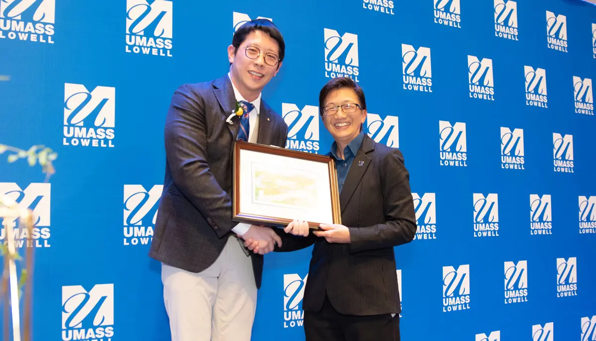 Fang Zhang receives the UMass Lowell Young Alumni Award from Chancellor Julie Chen.
