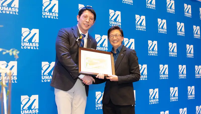 Fang Zhang receives the UMass Lowell Young Alumni Award from Chancellor Julie Chen.