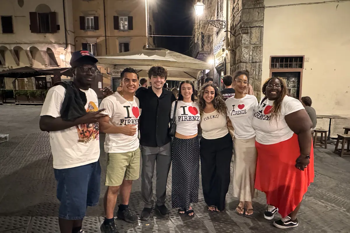 Seven young men and women pose for a group photo outside at night in a plaza in Florence, Italy.