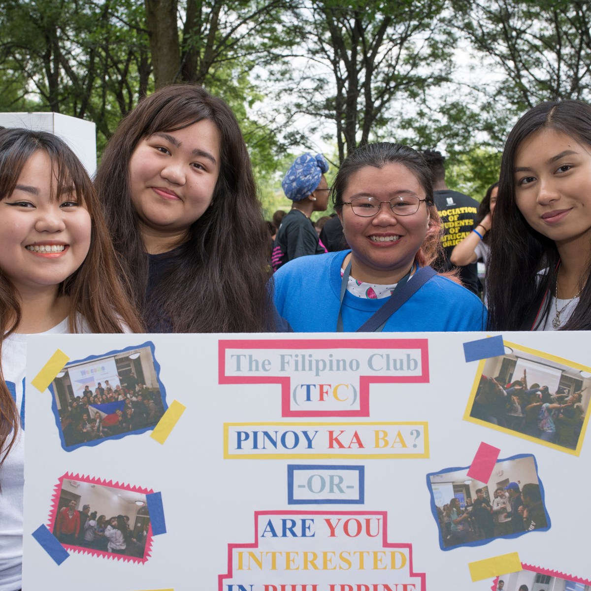 Four girls smile holding Filipino Club poster