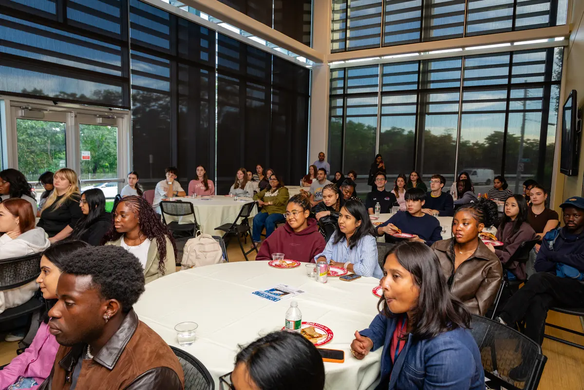 A roomfull of college students listen to a speaker.