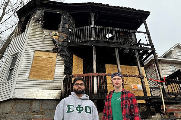 UML fraternity Sigma Phi Omicron brothers Rohan Solanki, left, and Arseniy Ohorilko in front of a nearby duplex that burned.