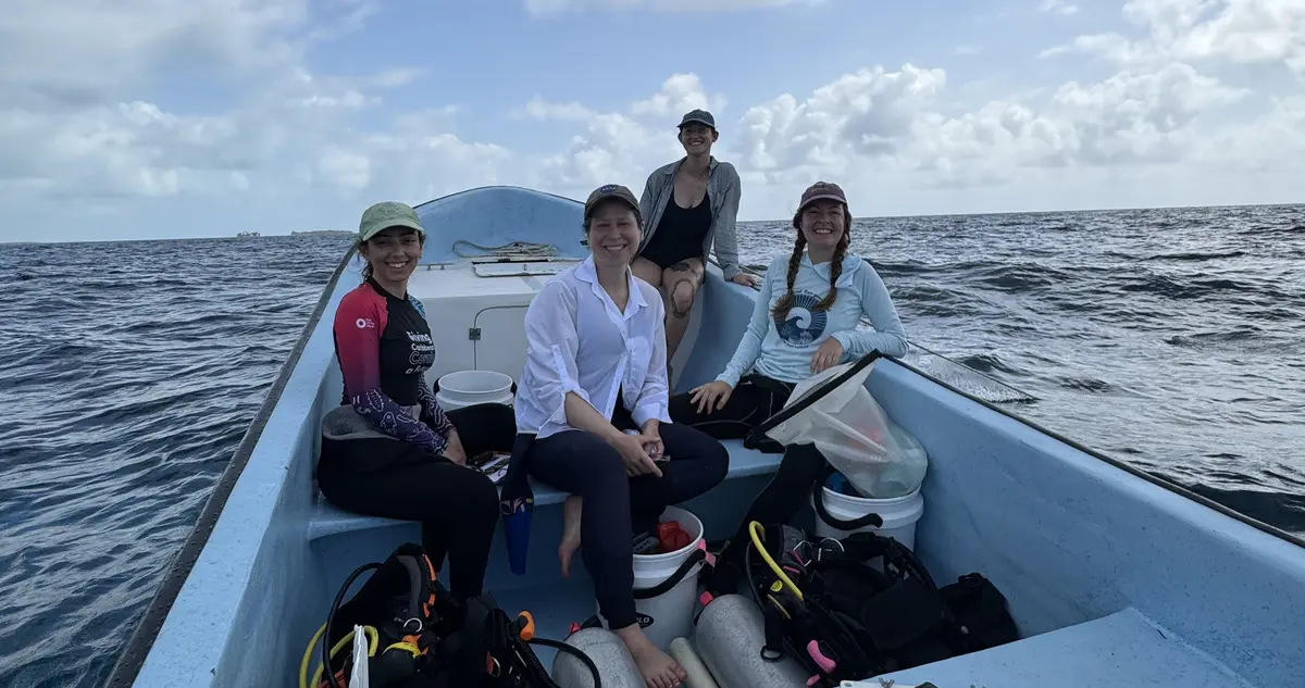 For women in dive suits and hats on a small boat