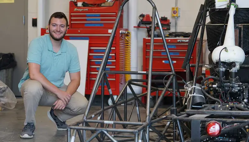 Garrett Perry next to equipment in the garage for River Hawk Racing